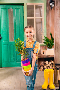 可爱的小女孩拿着多彩花盆和家用植物图片