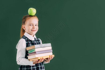 带着苹果头顶着苹果的漂亮小女学生拿着一堆书图片