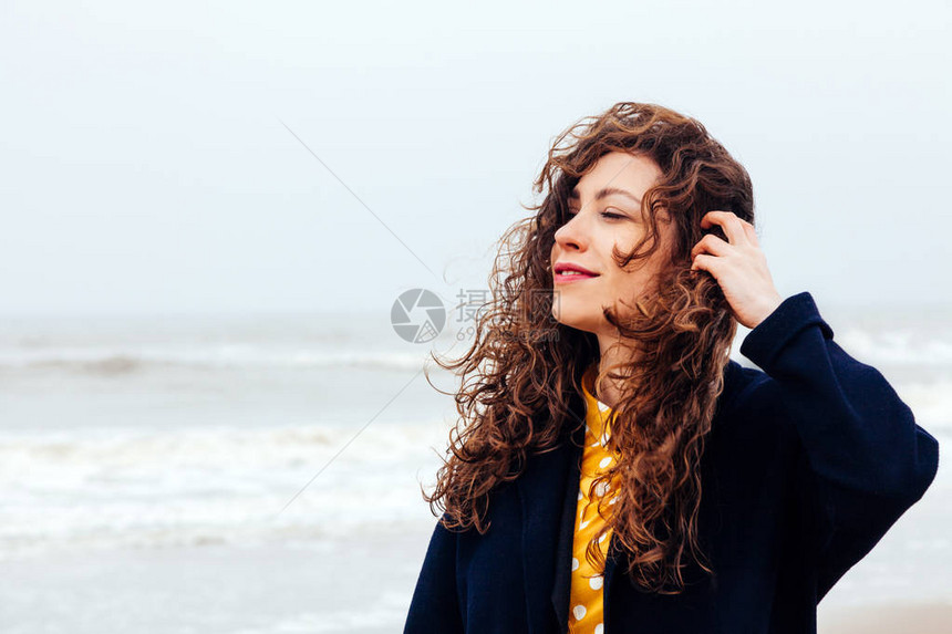 一个长的卷发女孩在寒冷的冬海中的特写镜头海上强风雨中图片