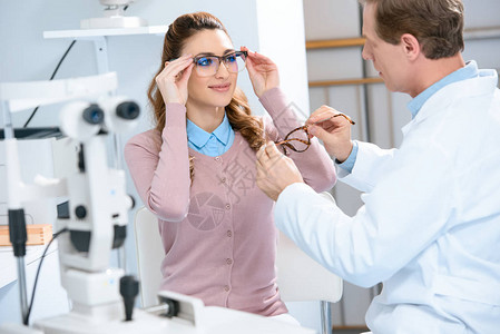 眼科医生帮助病人在诊所选择眼镜和图片