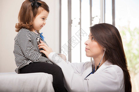 一位女儿科医生检查小女孩的呼吸和面对图片