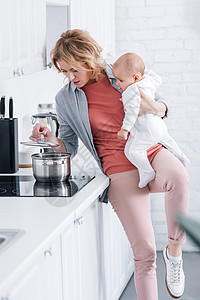 将可爱的婴儿抱在厨房做饭和厨图片