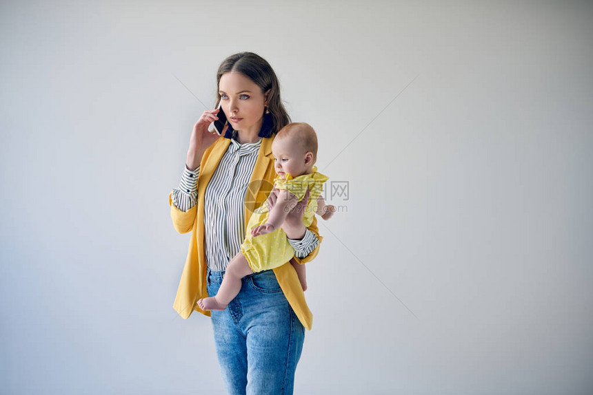 带着可爱的幼女和在灰色上被隔绝的智能手机聊天的图片