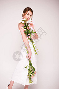 穿着白裙子的漂亮美女拿着鲜花看着灰图片