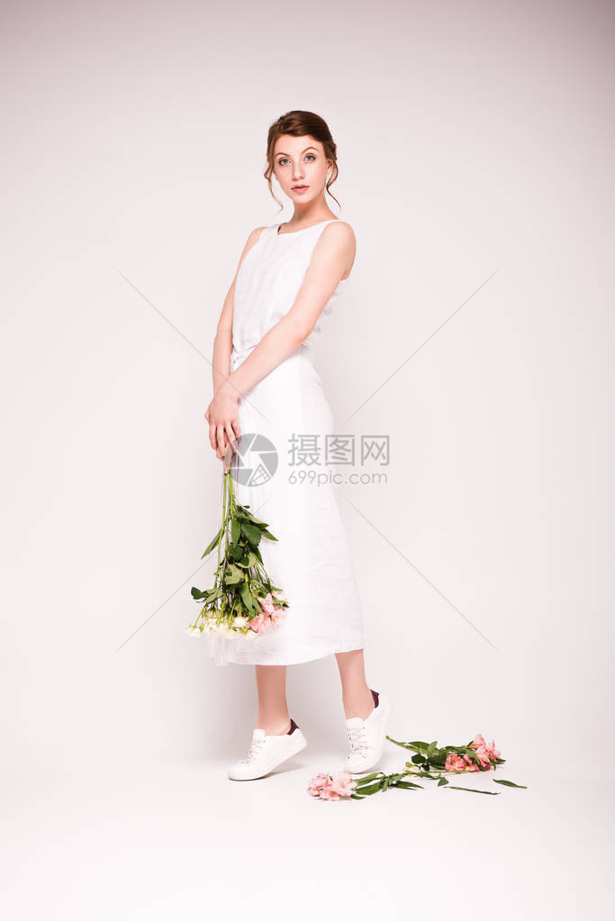 身着白裙子的漂亮年轻美女拿着美丽的鲜花图片