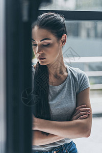 压抑的年轻黑头发女人站在窗图片