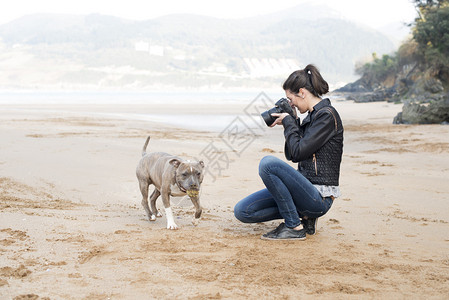 女人给你的狗拍照图片