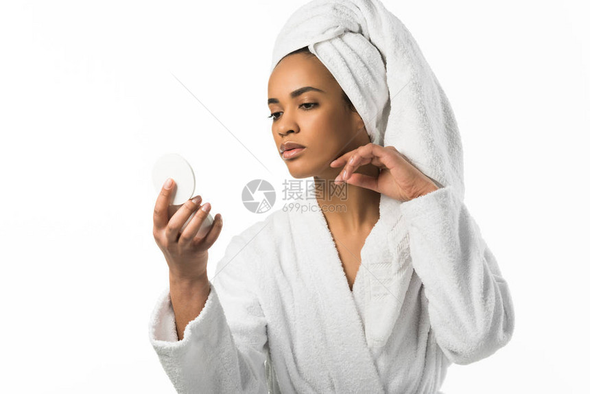 穿着浴袍和毛巾的非裔美国女人看着镜子照着干净的皮肤图片