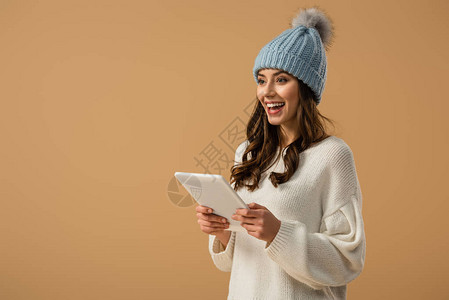 穿着编织帽子的卷发女孩拿着数字平板电脑图片