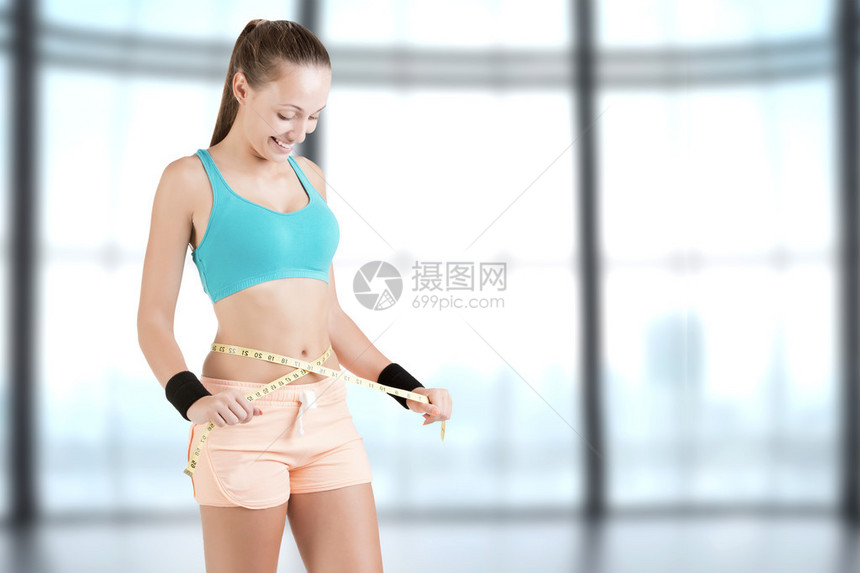 用黄色卷尺测量腰部的女人图片