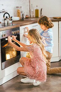 可爱的孩子们在厨房里看着烤炉图片