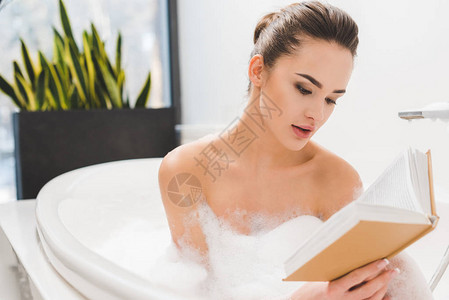 年轻女子一边洗澡一边看书的肖像图片