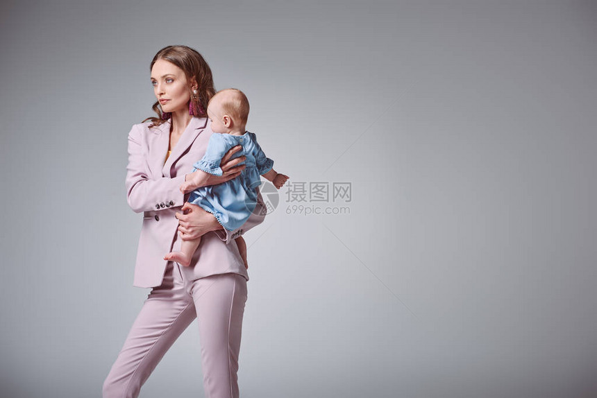 美丽的时尚年轻母亲带着可爱的幼女望着孤图片