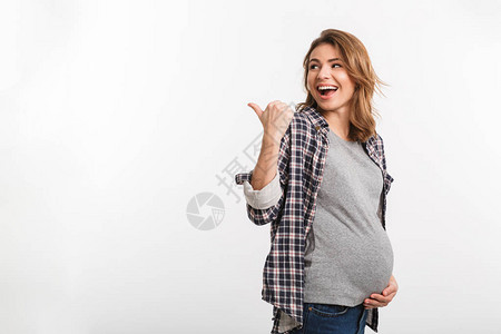 快乐的孕妇的肖像指着远处灰色孤立图片