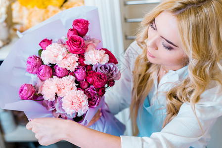 在花店里拿着鲜花束和玫瑰与康乃馨的图片