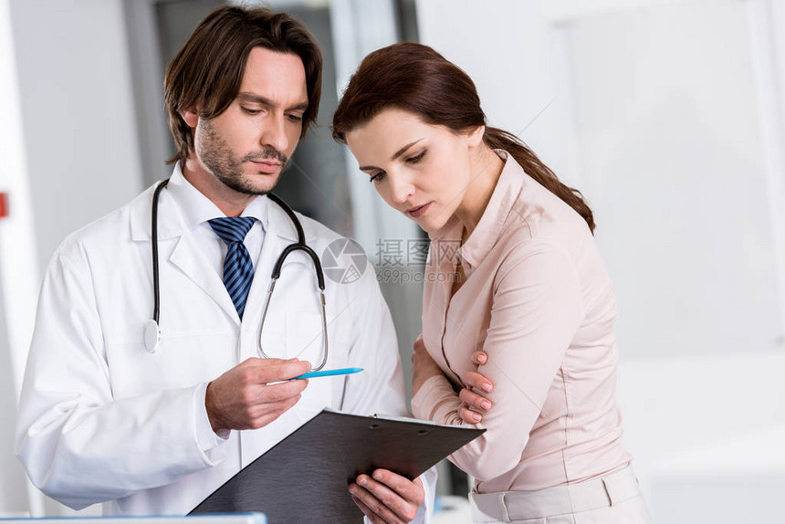 带听诊器的医生和看剪贴板的病人图片