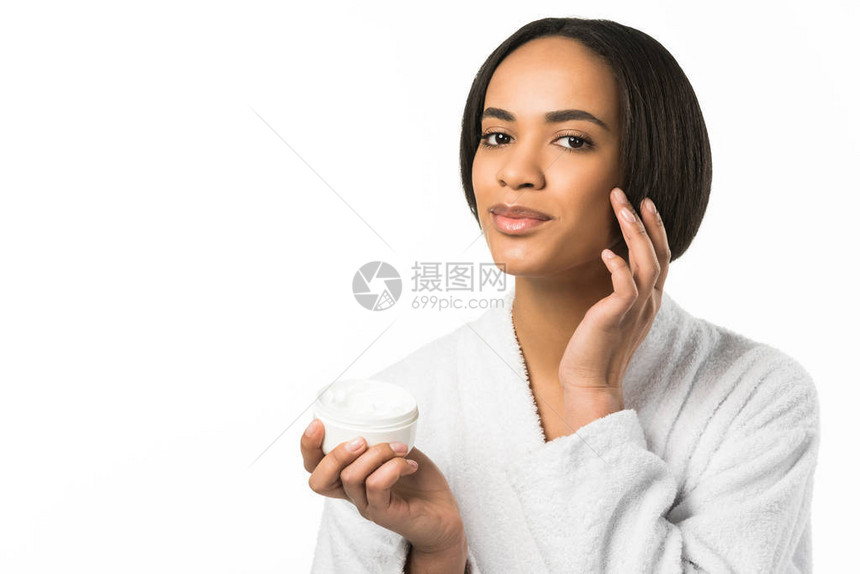 浴袍中的非洲美裔女在脸部施皮肤霜在图片
