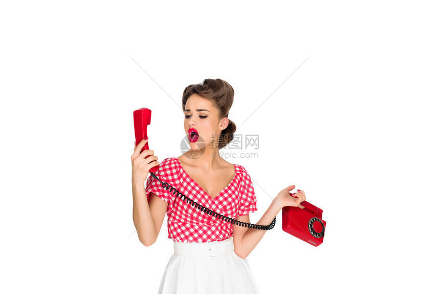 震惊的女人用白色的旧电话接着被图片