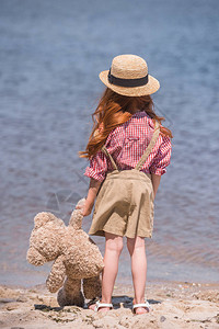 红发小姑娘身戴草帽站在海滨时图片