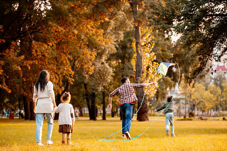 带着孩子在秋季公园放风筝的家庭图片