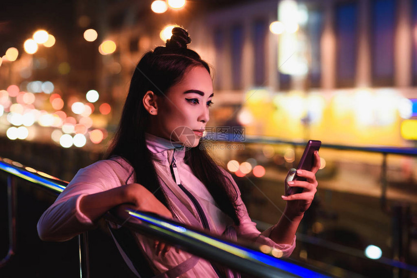 在街上使用智能手机的有吸引力的亚洲女孩图片