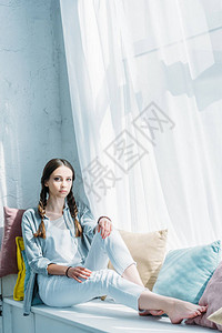 美丽的少女坐在有枕头的窗台上图片