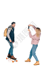 年轻女子手持智能手机拍摄带背的长板微图片