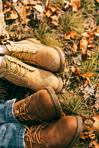 秋季美丽树叶中两双橙色靴子的俯视图图片