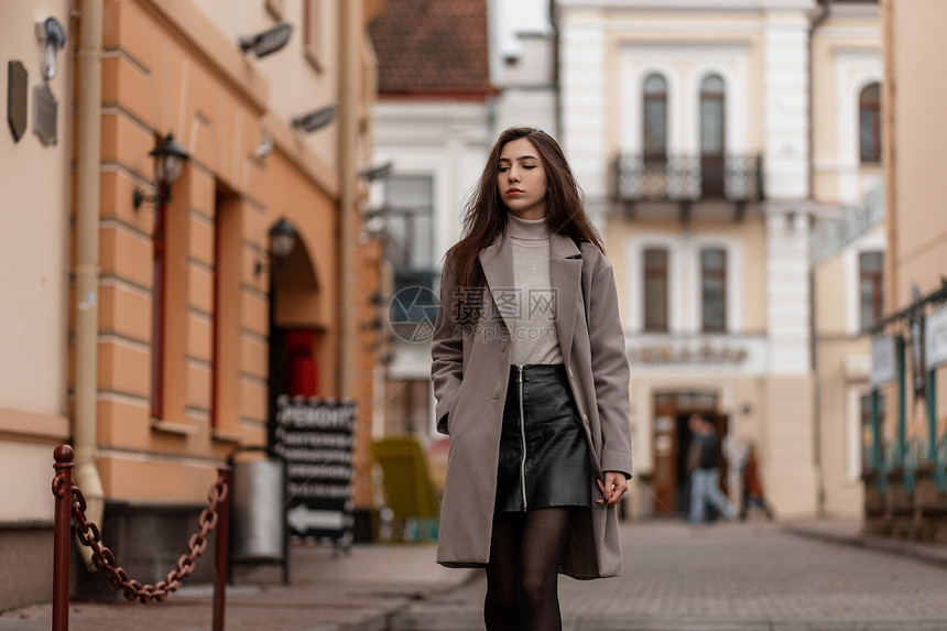 美丽的年轻女子穿着时髦的外套走在街上穿着时髦衣服的可爱女孩模特正在靠近老式建筑的城市旅行时尚新图片