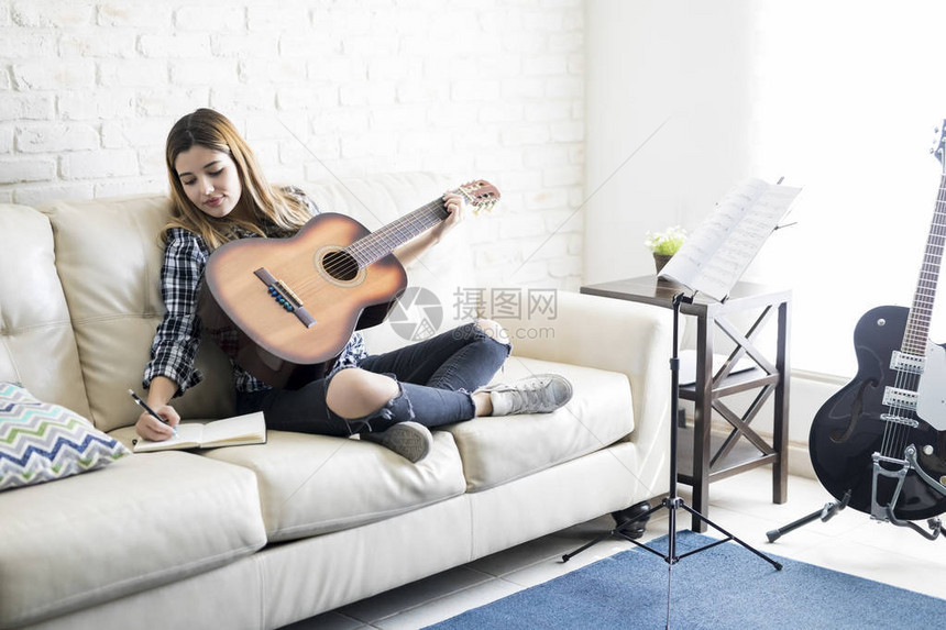 有魅力的女吉他手坐在沙发上图片