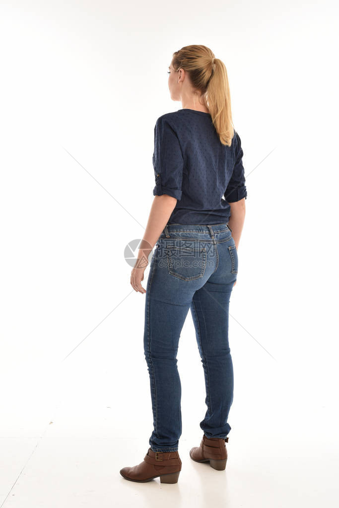 穿着简单的蓝色衬衫和牛仔裤的金发女孩全长肖像图片