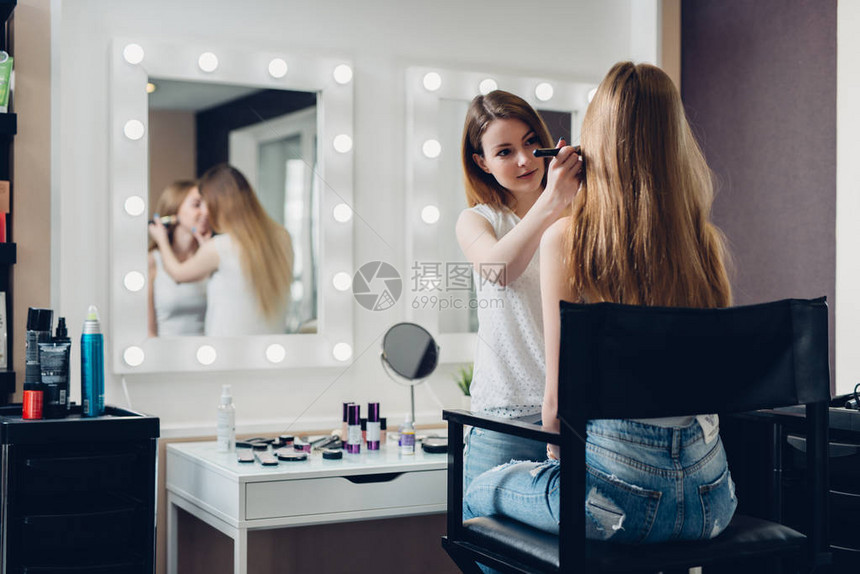 专业化妆师在美容院里做年轻女孩的自然美貌工作图片