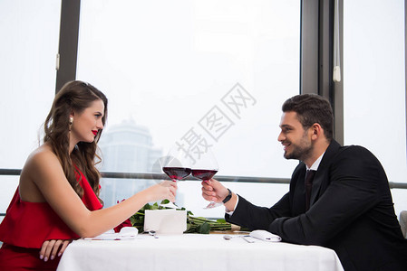 一对夫妇在餐厅庆祝情人节时碰杯红酒的侧面图图片