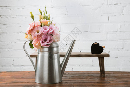水罐中美丽的鲜花和小凳子在木质表面布图片