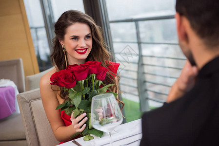 在浪漫约会时和在情人节餐厅的男朋友在一起带着一束玫瑰图片