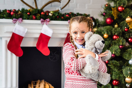 可爱的快乐孩子拥抱泰迪熊在圣诞节时图片