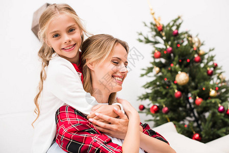 美丽的幸福母亲和女儿在圣诞节时抱图片