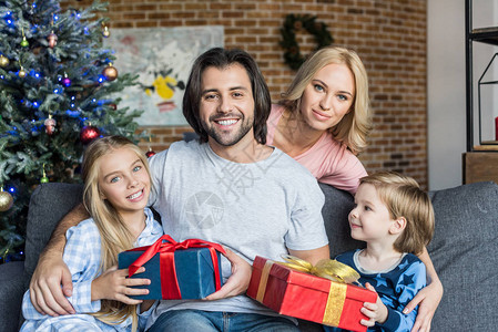 穿着睡衣的快乐父母和可爱孩子带着圣诞节礼物图片