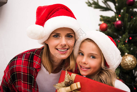 戴着圣诞礼帽的幸福母亲和女儿带着圣诞节礼物图片