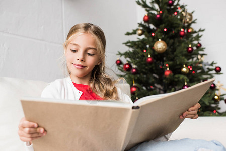 在圣诞节读书的可爱笑小女孩的图片
