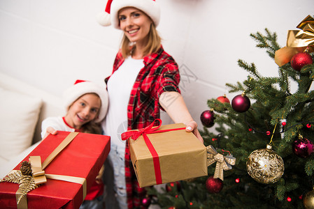 戴着圣诞礼物的圣塔帽子的母亲和女儿在摄影背景图片