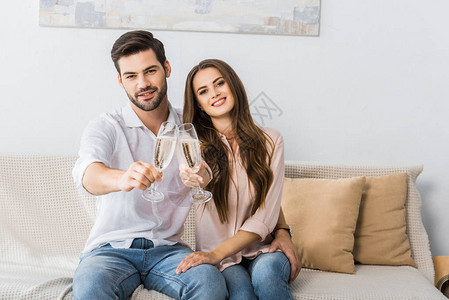 年轻夫妇在新家的沙发上碰杯香槟图片