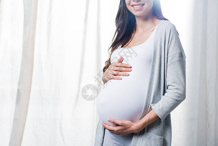 微笑的孕妇用手抚摸腹部图片