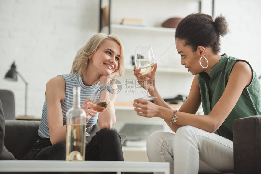 两个微笑着的多文化年轻女坐在白葡萄图片