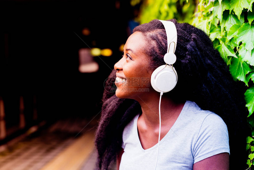 城市户外用智能手机监听音乐音乐放松概念的年轻美丽的女图片