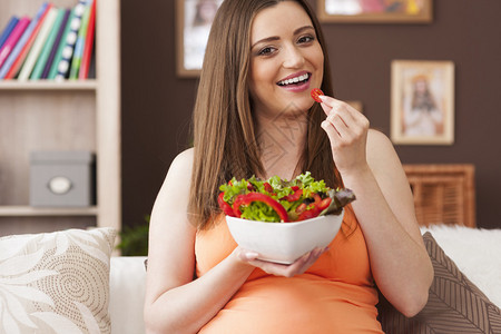 吃健康沙拉的愉快的孕妇图片