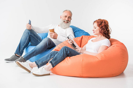 使用数字平板和智能手机喝咖啡的成年夫妇图片