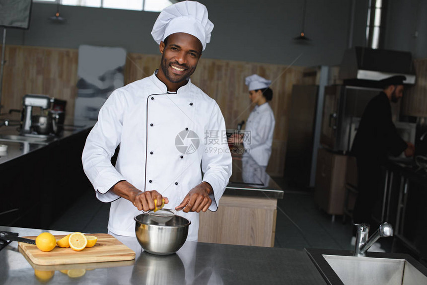 英俊的非洲厨师在餐厅厨房挤柠檬图片