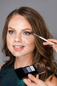 化妝師用眼沙ow对模型施以眼水的裁剪肖像片在灰图片