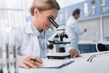 白大衣女科学家在化学实验室进行显微镜分图片